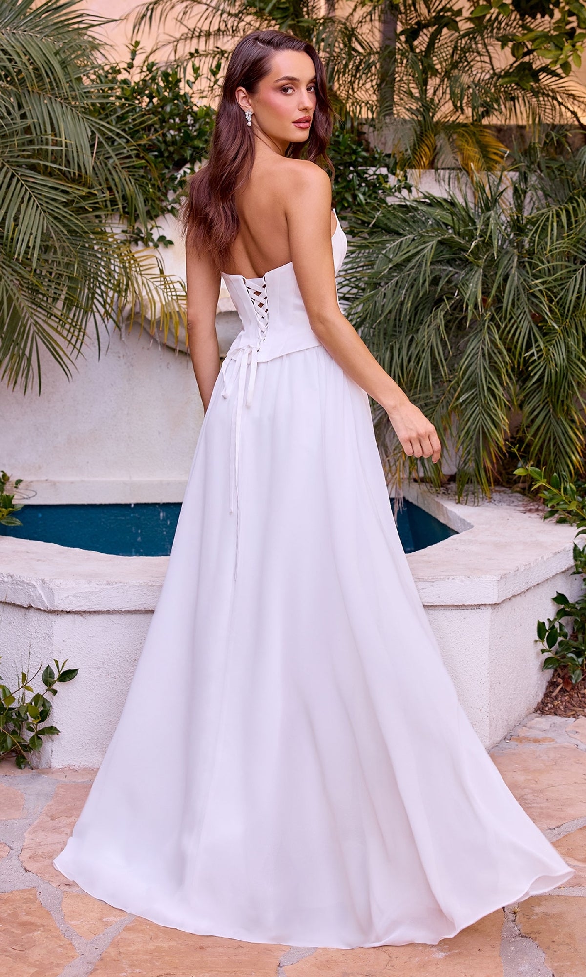 Woman in a white dress standing outdoors with greenery in the background